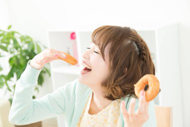 Kadın oturma odasında donut yiyor.