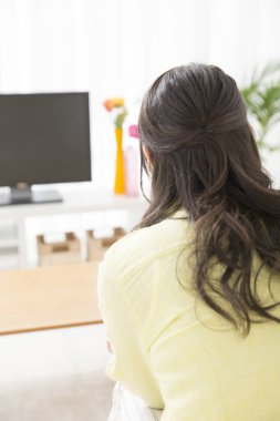Genç Asyalı kadın televizyon izliyor.
