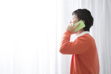 Evde akıllı telefon kullanan genç bir Asyalı. 