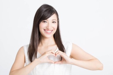 Genç, güzel Asyalı bir kadın, beyaz arka planda kalbi olduğunu gösteriyor. 