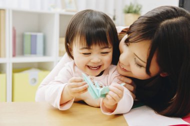 Anne ve kızı kağıt oyuncakla oynuyorlar. 