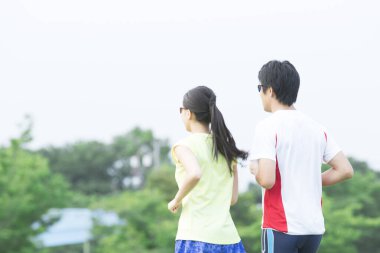 Sportif genç Asyalı çift parkta koşuyor.