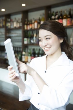 Restoranda tablet kullanan neşeli Asyalı garsonun portresi
