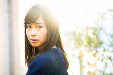 Sokakta kameraya bakan Asyalı kadın.