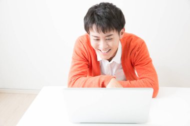 Genç Japon adam dizüstü bilgisayarla çalışıyor.