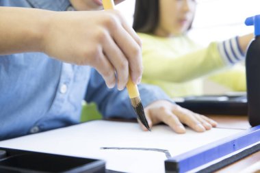 Fırçalı Asyalı öğrenci hiyeroglifleri yazmayı öğreniyor.