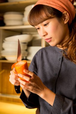 Asyalı genç bayan garson mutfakta havuç soyuyordu.
