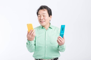 Cep telefonu ve akıllı telefon tutan usta Asyalı adam, stüdyo fotoğrafı.