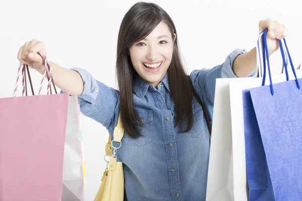 白い背景に隔離されたショッピングバッグを示す美しい笑顔の日本人女性 — ストック写真