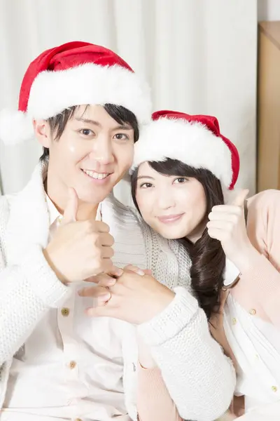 亚洲夫妇戴着圣诞礼帽在家里庆祝新年 — 图库照片
