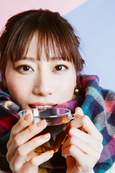 asian female in a plaid scarf with tea, studio shot