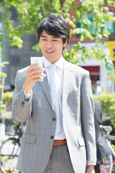 Yakışıklı Gülümseyen Asyalı Adamı Sokakta Cep Telefonu Kullanıyor — Stok fotoğraf