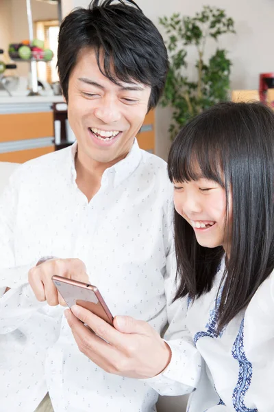 Χαμογελαστός Πατέρας Και Κόρη Χρησιμοποιώντας Smartphone Στο Σπίτι — Φωτογραφία Αρχείου
