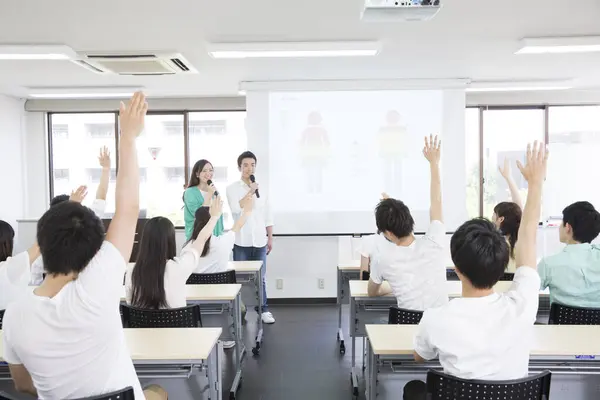 Asian students with microphones making presentation during lesson