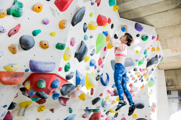 Güzel Japon kadın spor salonunda duvara tırmanıyor. 