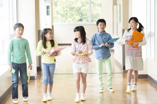 Grupa Japońskich Dzieci Książkami Spacerującymi Korytarzu Szkolnym — Zdjęcie stockowe