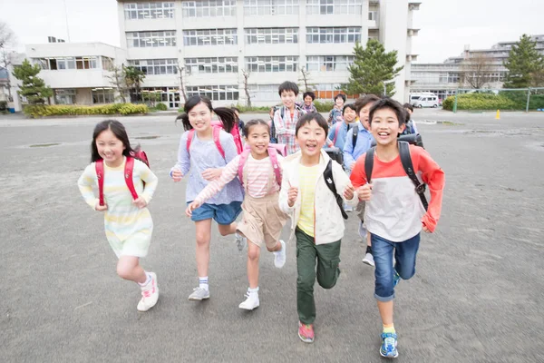 Grupa Japońskich Dzieci Plecakami Biegającymi Szkolnym Podwórku — Zdjęcie stockowe