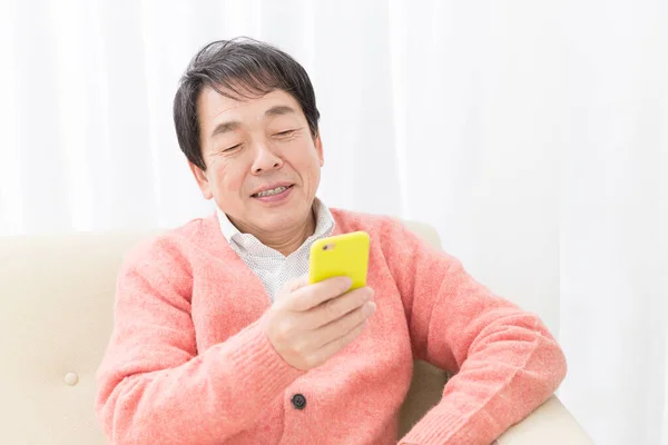 asian senior man with smartphone at home