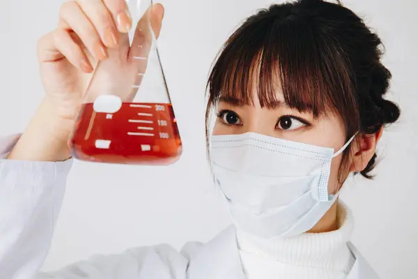 Young asian woman scientist wearing facial mask working. Studio shot