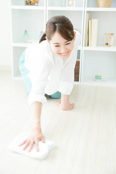 若い女性は家を掃除し 若いアジアの主婦はラグで床を拭きます — ストック写真