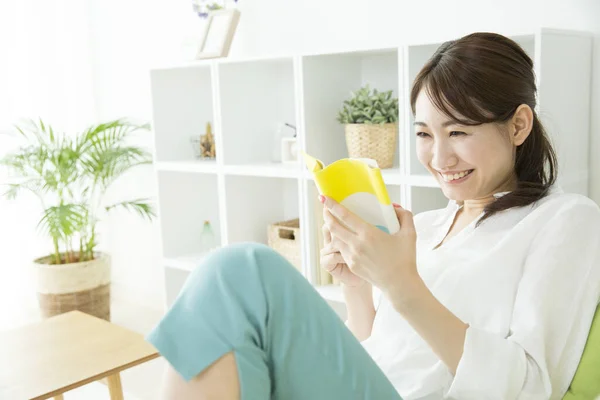 Hymyilevä Aasialainen Nainen Lukeminen Kirja Kotona — kuvapankkivalokuva