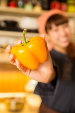 Mutfakta turuncu dolmalık biberli Asyalı kadın