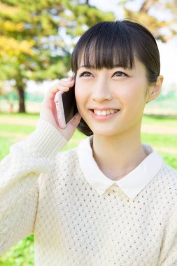 Açık havada akıllı telefonları olan Japon bir kızın portresi.