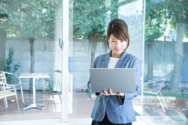 Modern ofiste dizüstü bilgisayar kullanan güzel bir Japon iş kadını.