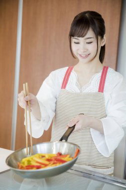 Kadın mutfakta yemek hazırlıyor, biber kızartıyor. 