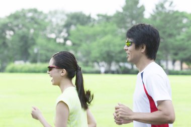 Sportif genç Asyalı çift parkta koşuyor.