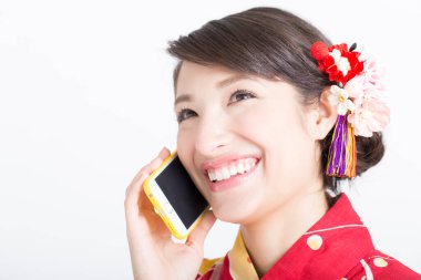 Geleneksel Japon elbiseli Asyalı genç kadın akıllı telefondan konuşuyor.