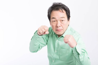 Yumrukları havada, dövüşmeye hazır, beyaz tenli Asyalı kıdemli adam. 