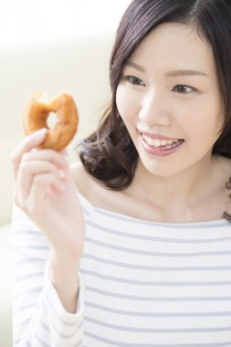 Güzel Asyalı kadın lezzetli çörekler yiyor.