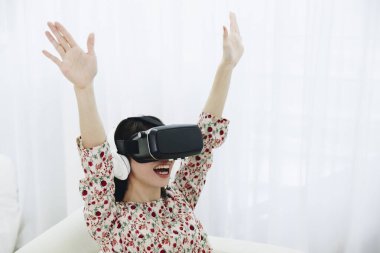 Sanal gözlük takan Asyalı kız eğleniyor.