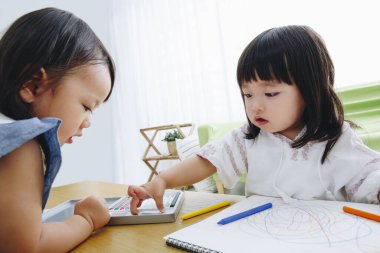 Asyalı küçük kızlar evde resim çiziyor.