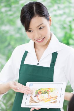 Asyalı garson restorandaki tablette menüyü gösteriyor