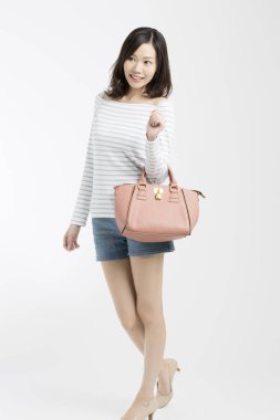 Güzel bir Japon kadının el çantasıyla beyaz arka plana bakarken çekilmiş bir fotoğrafı. 