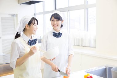 Parlak mutfakta birlikte yemek yapan iki kadın.