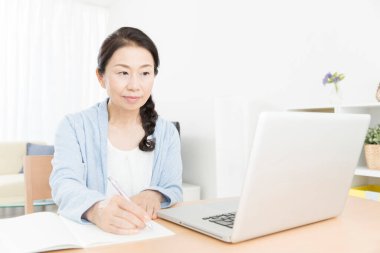 Evde dizüstü bilgisayar kullanan yaşlı bir kadının portresi