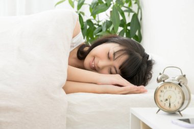 Güzel genç Asyalı kadın yatakta uyuyor.