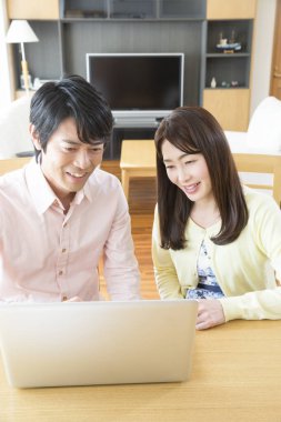 Mutlu Asyalı çift evde dizüstü bilgisayar kullanıyor.