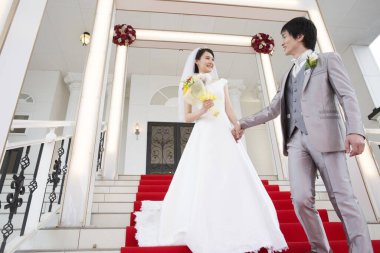 Merdivenlerde poz veren mutlu Asyalı gelin ve damadın portresi.