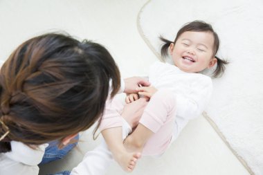 Asyalı anne yerde kızıyla oynuyor.