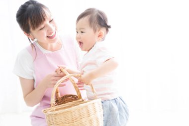 Asyalı anne ve küçük kızı tahta sepetlerle oynuyorlar. 