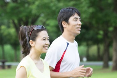 Sportif genç Asyalı çift parkta koşuyor.