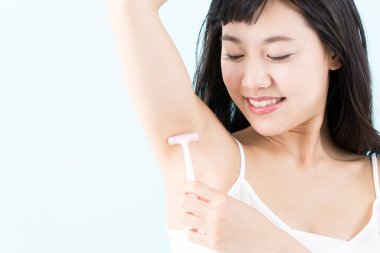 Tüylerini aldırmak için koltuk altını tıraş eden genç bir kadın.