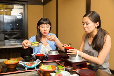 Güzel Asyalı kadınlar restoranda geleneksel Japon yemekleri yiyorlar.