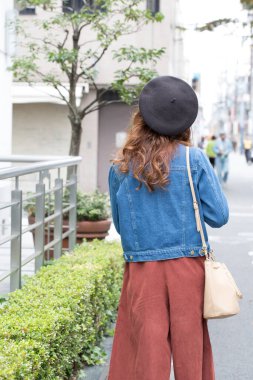 Şapkalı genç bir kadın sokak arkasındaydı. 