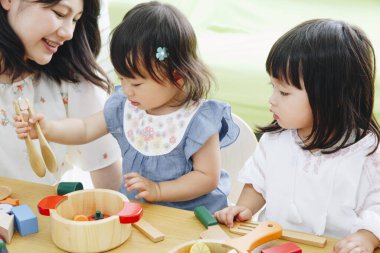 Çocuklar ahşap mutfak oyuncaklarıyla oynuyor.