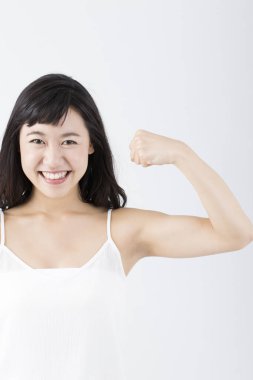 Genç Asyalı kadın beyaz arka planda güçlü pazılar gösteriyor.